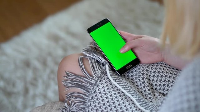 Female hand swiping up on a phone with a green screen