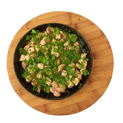 Roasted meat with greens on a frying pan standing on a wooden Board isolated on white