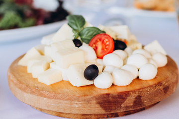 cheese plate with a bunch of grapes, honey and nuts. Gouda, parmesan, mozzarella, gorgonzola on a wooden board.
