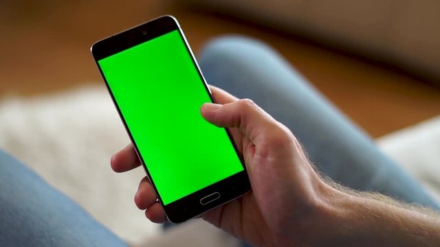 Male hand swiping up on a phone with a green screen