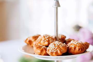 Pies with sesame seeds on a multi-tiered plate. Buffet table at the party.