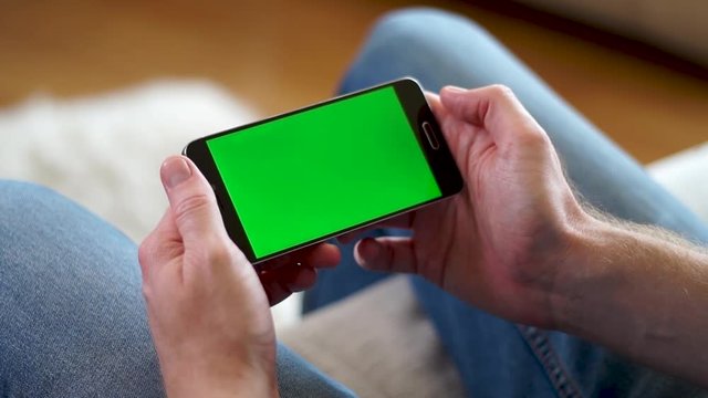 Male hands holding a phone with a green screen horizontally and watching a video