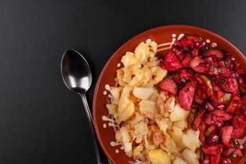 Boiled chopped potatoes and vegetable salad on clay plate. View from above