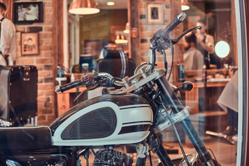 Fototapeta na wymiar Retro vintage motobike is parked inside at trendy barbershop.