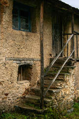 uneven stone stairs in an old house with grass and moss and wooden door frame