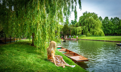 Girl sitting along River Cam near Kings College in the city of Cambridge, United Kingdom