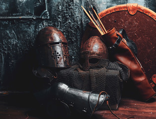 Still life with ancient shield, two rusted helmets, quiver of arrows and chain mail.