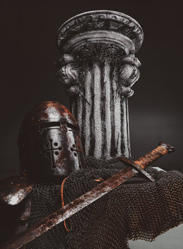 Still life at studio withs belt, ancient pedestal, rustes sword and two helmets.
