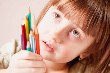 The world is colorful and wonderful. Humorous photo of great artist. Portrait of cute little child girl with colored pencils.
