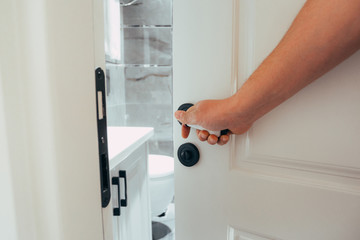 Closeup of hand holding metal doorknob on wooden door