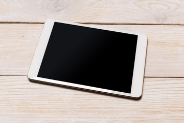 White digital tablet on wooden table. Top view with copy space.