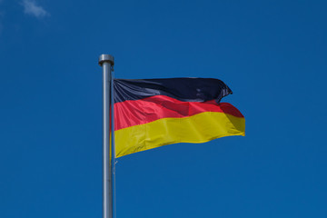 photograpy of a waving flag of Germany against blue cloudless sky