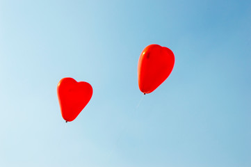 Fototapeta na wymiar Heart shaped balloons and are flying high in the wind