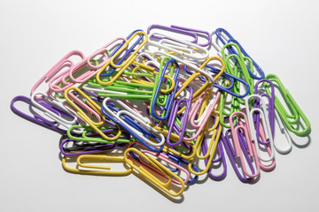 Multicolored paper clips in a plastic coating lie on a white background.