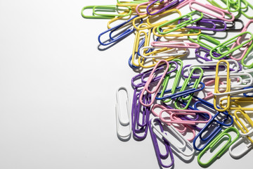 Multicolored paper clips in a plastic coating lie on a white background.