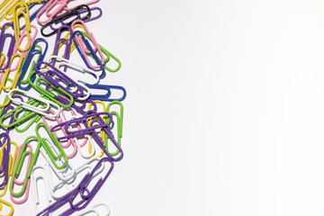Multicolored paper clips in a plastic coating lie on a white background.