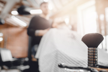 Barbershop, brush for shaving beard along with bowl, blurred background of hair salon for men