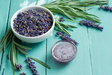 a pile of fresh lavender flowers and syrup on blue wooden table background