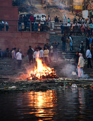 A funeral pyre of a dead body being cremated by the banks of the River Ganga on the Manikarnika...