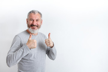 Adult happy gray-haired man with a beard showing thumbs up on a white background, free method for text