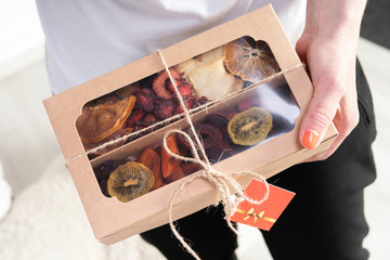Box of marshmallow and dried fruit in the hands of a girl