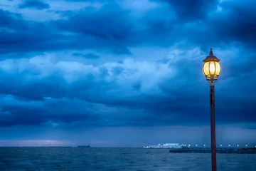 Fotobehang Light Post at nigth near sea with stom background © CHOKCHAI