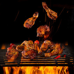 Tasty chicken legs and wings on the grill with fire flames © Lukas Gojda