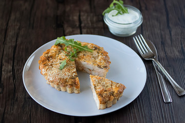 Chicken meat pie with greens and sesame with tartar sauce on a brown wooden table.