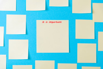 Blank yellow sticky notes on a blue background, concept of business work. Yellow memo stickers on blue wall. Mock-up. The inscription is important.
