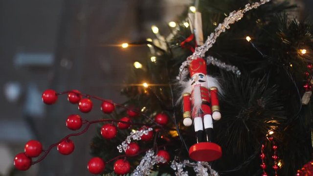 Close-up view of traditional Christmas holiday nutcrackers figurine hanging on a Christmas Tree near the lights and other decorations. Frame. Christmas mood