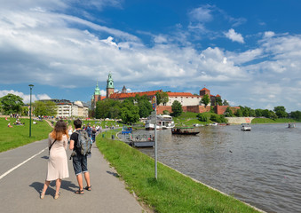 Spring view on Wawel Castle, Vistula River, spring park, bicycle lane and walking tourists