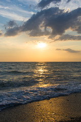 Amazing sea sunset on the pebble beach, the sun, waves, clouds