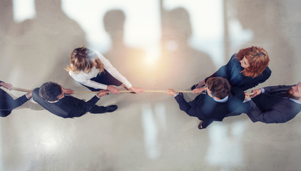 Rival business man and woman compete for the command by pulling the rope. double exposure