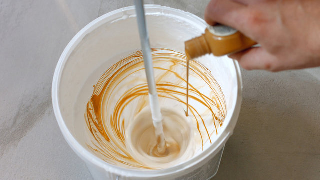 House Renovation Concept. Close Up Shot Of Mixing White And Brown Paint In Bucket.