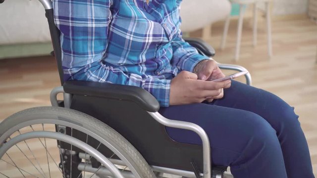 disabled african american woman in a wheelchair uses a smartphone