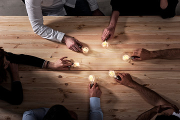 Teamwork and brainstorming concept with businessmen that share an idea with a lamp. Concept of...