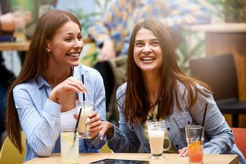 Two female friends talking and having fun at a coffee shop