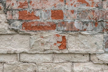 abstract background of an old brick wall with peeling plaster and the remains of pink paint close up