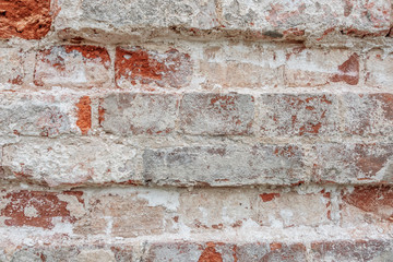 abstract background of an old brick wall with peeling plaster and the remains of pink paint close up