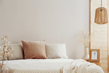 Beige and white pillows on comfortable bed, copy space on empty wall