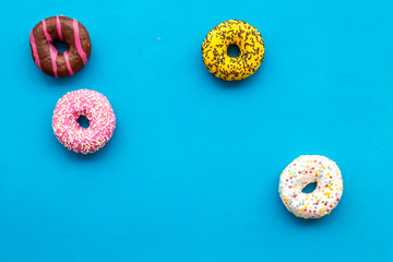 Donuts of different flavors for breakfast on blue background top view