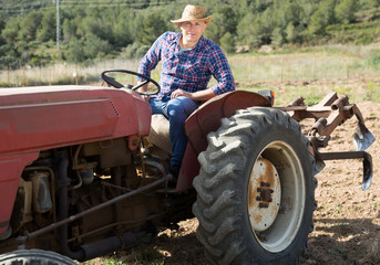 Positive man working on farm tractor