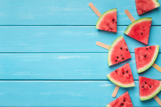 Watermelon triangles on wooden sticks, blue wood background