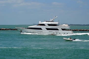 Fototapeta na wymiar White motor yacht exiting Government Cut in Miami Beach,Florida and heading towards open ocean.