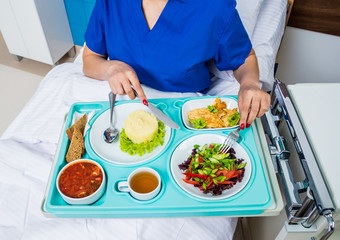 Tray with breakfast for the young female patient. The young woman eating in the hospital.
