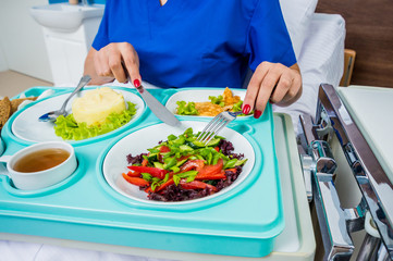 Tray with breakfast for the young female patient. The young woman eating in the hospital.