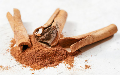 Closeup detail - natural cinamon bark sticks, with ground powder in front, on white board