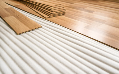 Tiles of laminated floor with wooden effect laying on white base foam, ready to be installed on ground, home improvement illustration photo