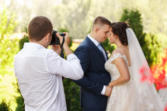 Wedding photographer takes pictures of the beautiful bride and groom outdoors