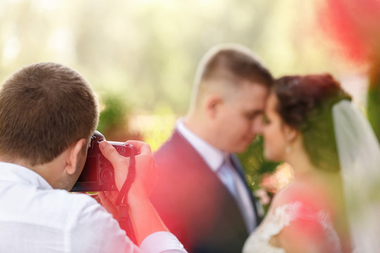 Wedding photographer takes pictures of the beautiful bride and groom outdoors